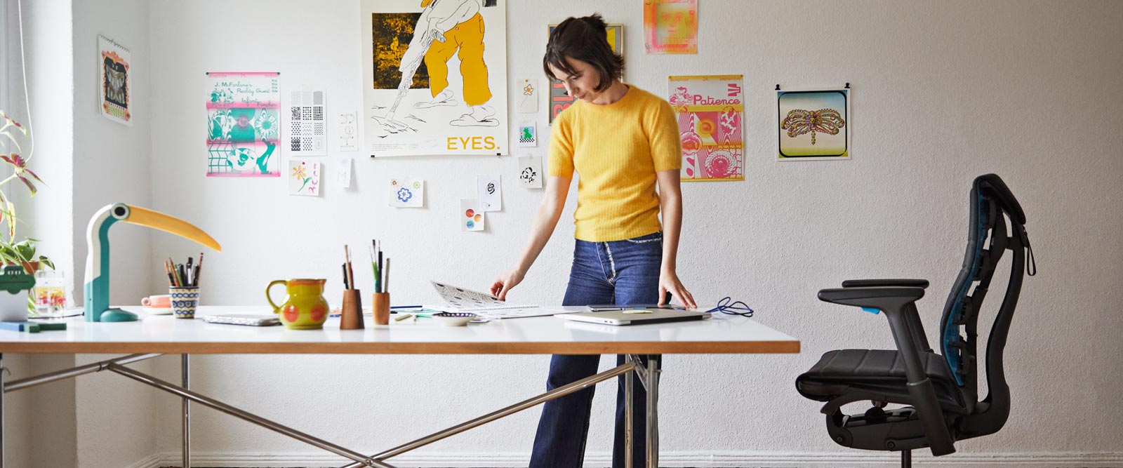 Die Illustratorin, Malerin und Autorin Molly Rose Dyson steht in ihrem Atelier mit einem Embody-Gaming-Stuhl in Schwarz und Cyanblau