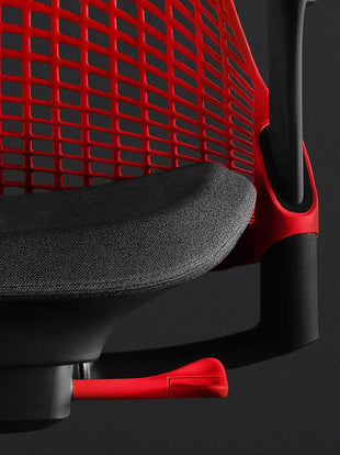Nahaufnahme der Vorderseite eines rot-schwarzen Sayl-Gaming-Stuhls von Herman Miller, die das konturierte Sitzpolster und die rote Rückenlehne zeigt.