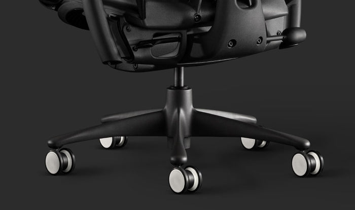 Nahaufnahme eines schwarzen Embody-Gaming-Stuhls von Herman Miller, mit den schwarzen und weißen Rollen.