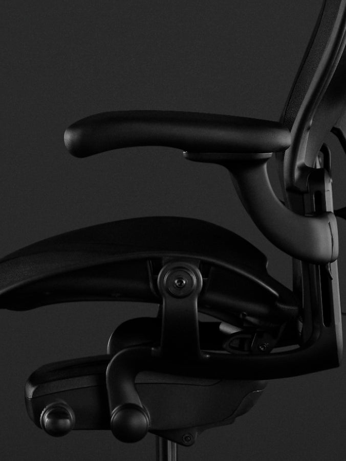 Seitenansicht eines schwarzen Aeron-Gaming-Stuhls von Herman Miller mit den voll verstellbaren Armlehnen.
