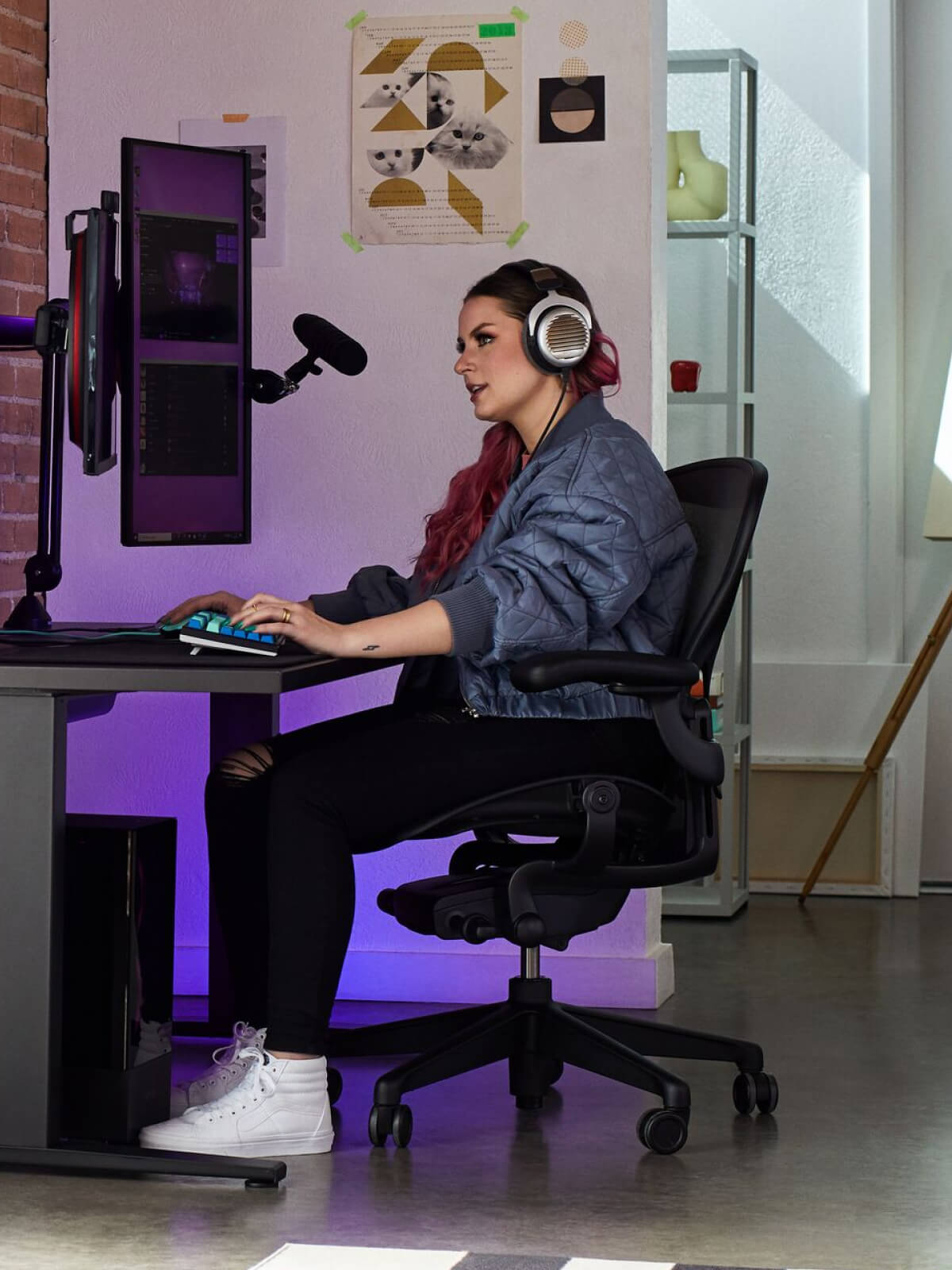 Electra beim Gaming auf einem Aeron in Onyx Black mit einem Nevi-Gaming-Tisch in Schwarz und einem Ollin-Monitorarm