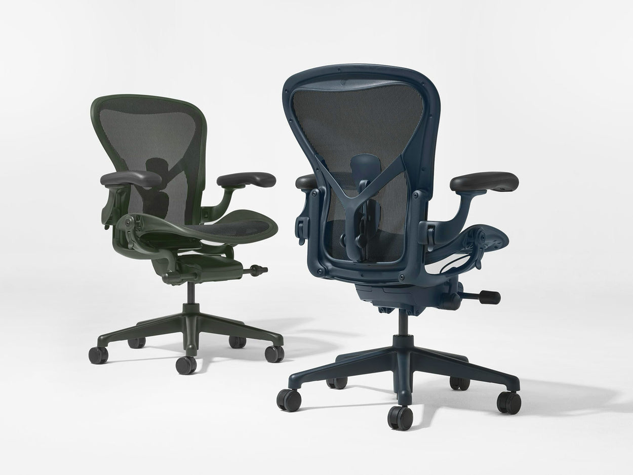 Zwei Herman Miller Aeron-Bürostühle in den Farben Jasper (Grün) und Nightfall (Blau), fotografiert in einem weißen Studio.