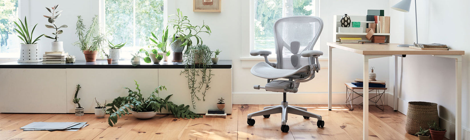 Herman Miller Aeron in Mineral mit OE1 Schreibtisch mit fester Höhe, weißem Gestell und Eschenplatte in einer hellen, pflanzengefüllten Home Office Umgebung