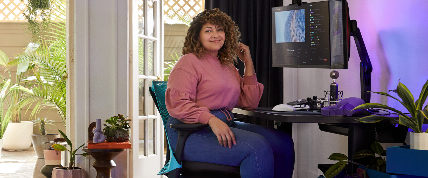 Foto des Profi-Gamers und Synchronsprechers Friskk, der an seinem Gaming-Setup auf dem Sayl-Gaming-Stuhl in Schwarz und leuchtendem Ozeanblau mit dem Nevi-Gaming-Tisch in Schwarz sitzt