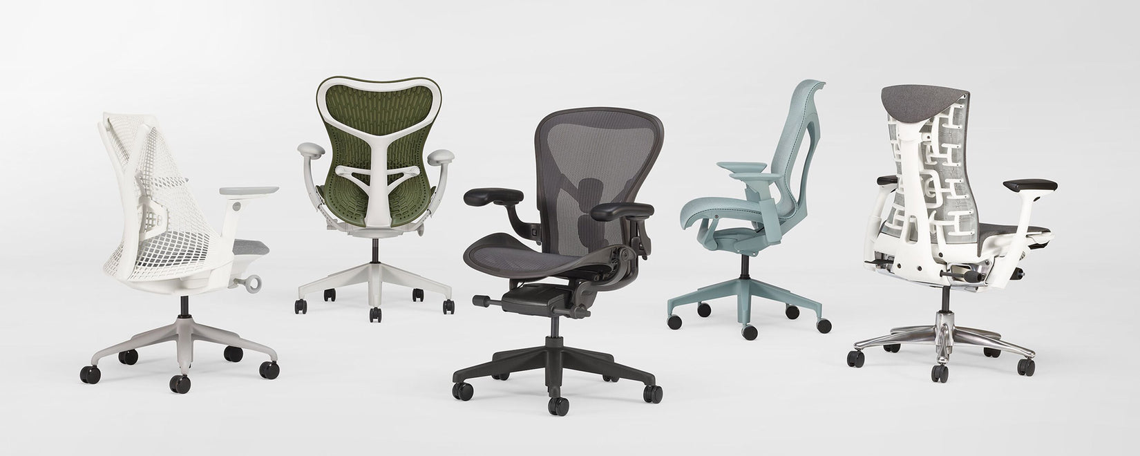 Eine Auswahl von fünf ergonomischen Bürostühlen von Herman Miller in einem weißen Studio. Zu sehen sind: Sayl, Mirra 2, Aeron, Cosm und Embody.