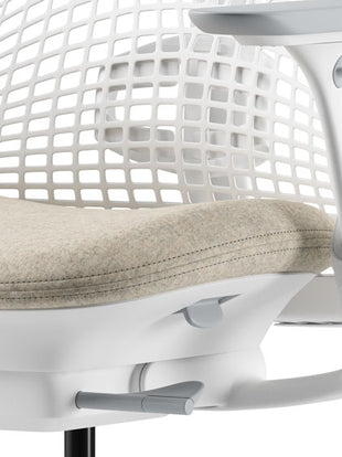 Nahaufnahme eines beige-weißen Sayl-Bürostuhls von Herman Miller, die den konturierten Sitz zeigt.