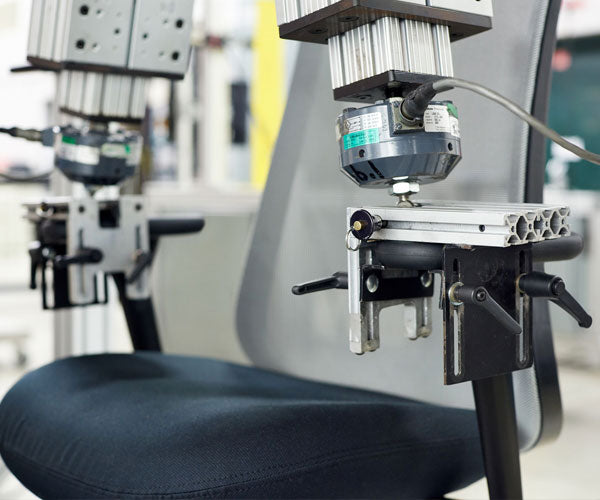 Foto eines Tests mit zwei Armlehnen, der das Gewicht, den Druck und die Abnutzung nachbildet, die alle Herman Miller Stühle durchlaufen.