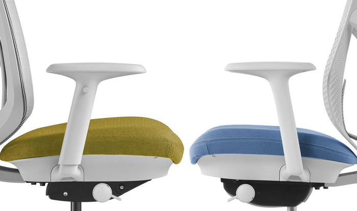 Seitenansicht zweier Herman Miller Verus-Bürostühle, die sich gegenüberstehen. Der linke Stuhl zeigt die voll verstellbare Armlehne, der rechte Stuhl die feste Armlehne.