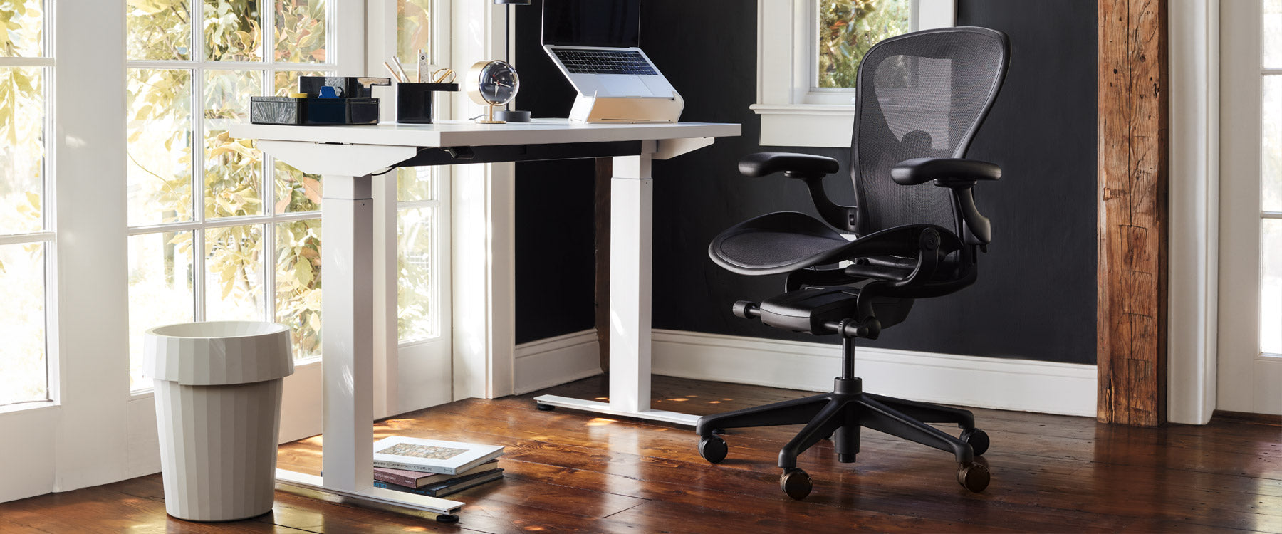 Homeoffice-Szene mit einem weißen Steh-Sitz-Schreibtisch von Nevi, einem Bürostuhl von Aeron in Onyx-Schwarz, einem Laptopständer von Oripura und einem Abfallbehälter von Hay Shade in Off-White