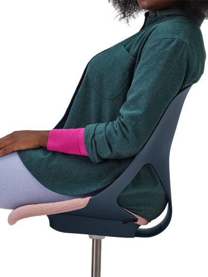 Seitenansicht einer Person, die in einem blauen Zeph-Bürostuhl von Herman Miller mit rosa Sitzpolster sitzt.