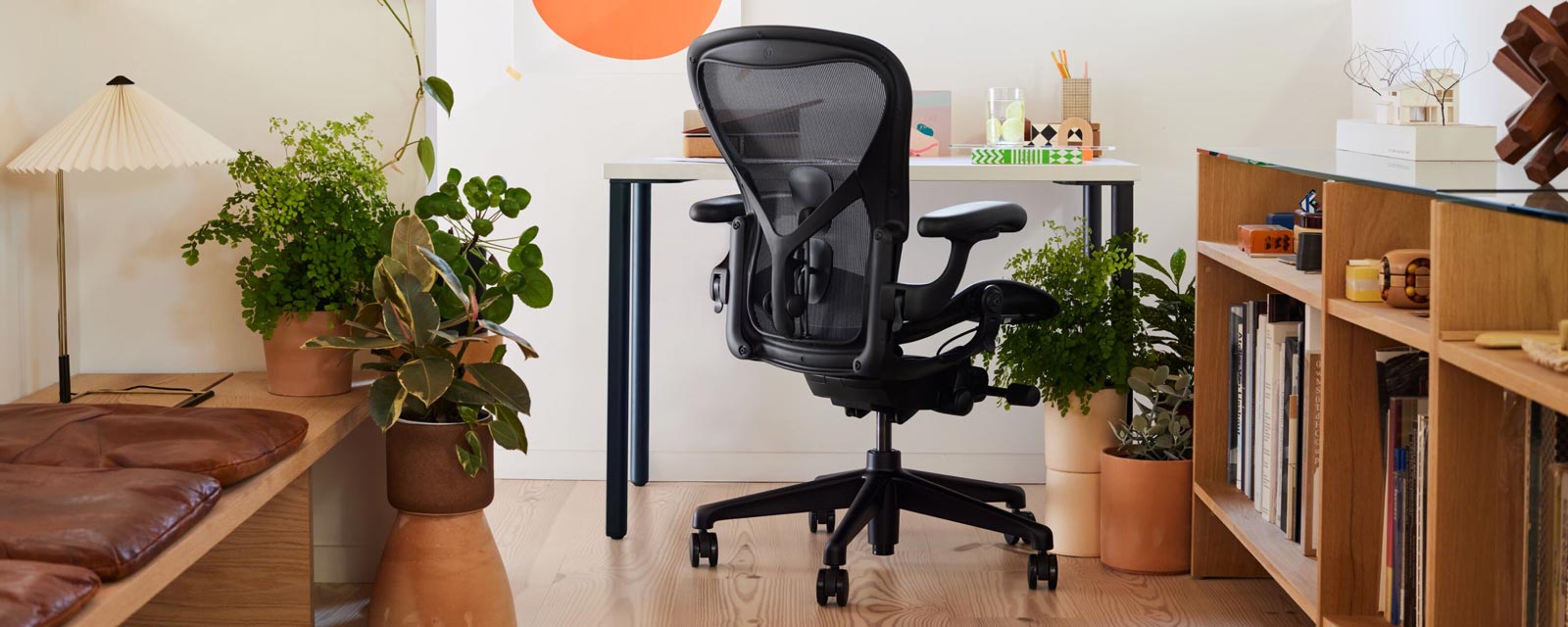 Heimbüro mit dem Aeron-Bürostuhl Iconic in Schwarz vor einem kleinen OE1-Schreibtisch mit blauen Beinen und weißer Platte, Im Zimmer steht auch eine Hay Matin Tischlampe