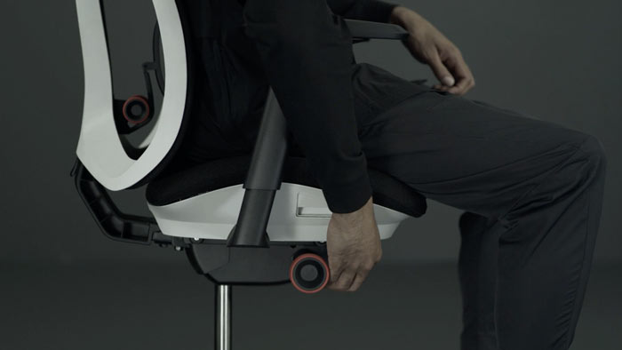 Ein Video von einer Person, die in einem weißen und schwarzen Vantum-Gaming-Stuhl von Herman Miller sitzt und neben den Stuhl greift, um die Sitzhöhe einzustellen.