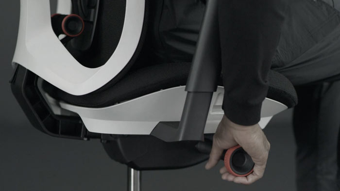 Ein Video von einer Person, die in einem weißen und schwarzen Vantum Gaming-Stuhl von Herman Miller sitzt und neben den Stuhl greift, um die Neigungsspannung einzustellen.