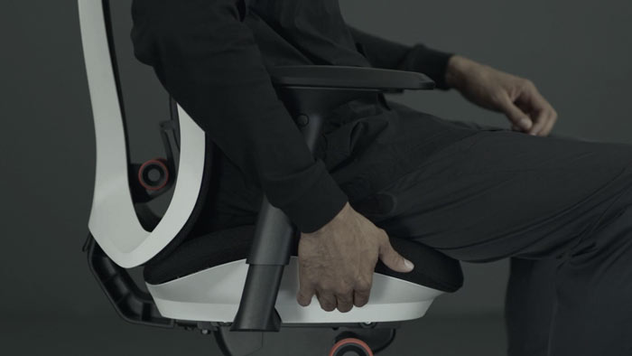 Ein Video von einer Person, die in einem weißen und schwarzen Vantum-Gaming-Stuhl von Herman Miller sitzt und neben den Stuhl greift, um die Sitztiefe einzustellen.