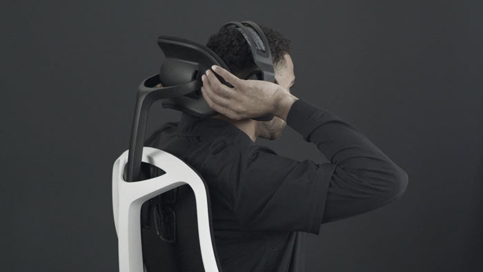 Ein Video von einer Person, die in einem weißen und schwarzen Vantum Gaming Chair von Herman Miller sitzt und hinter den Stuhl greift, um die Kopfstütze einzustellen.