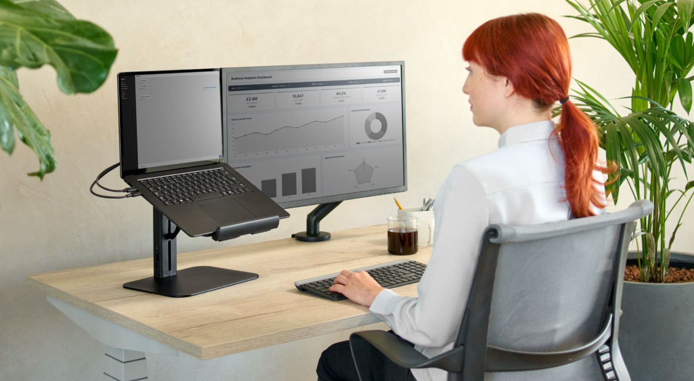 Eine Frau nutzt eine Homeoffice-Ausstattung mit einem Nevi-Schreibtisch, einem Setu-Stuhl und einem Lana-Laptopständer.