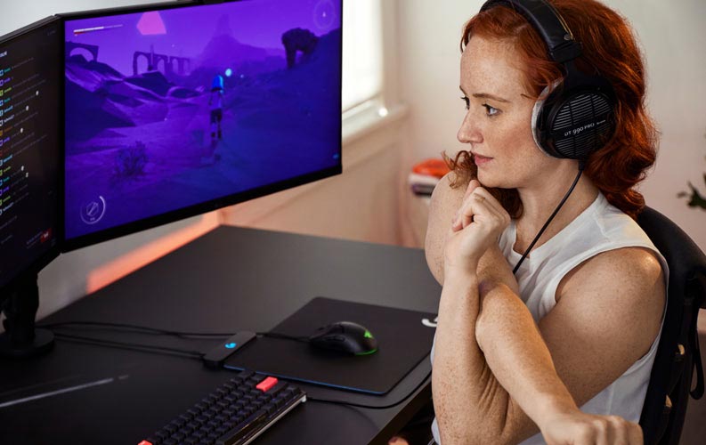 Die Esports-Ärztin Lindsey Migliore vor einem Gaming-Setup mit zwei Monitoren auf Ollin-Monitorarmen