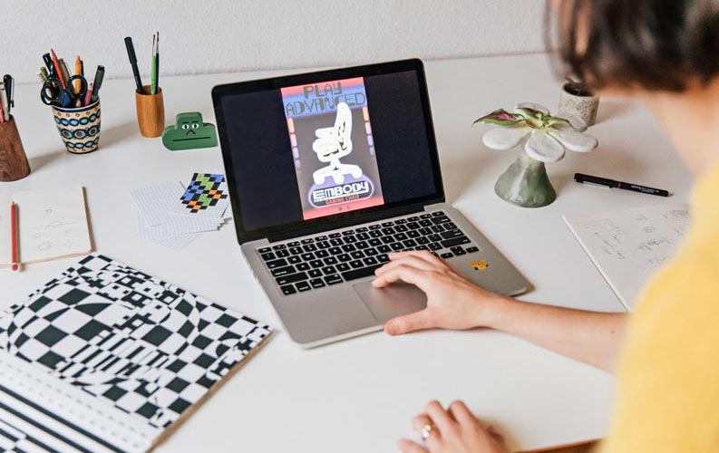 Die Designerin Molly Rose Dyson bei der Arbeit an einem Herman Miller Embody-Plakat auf einem Laptop