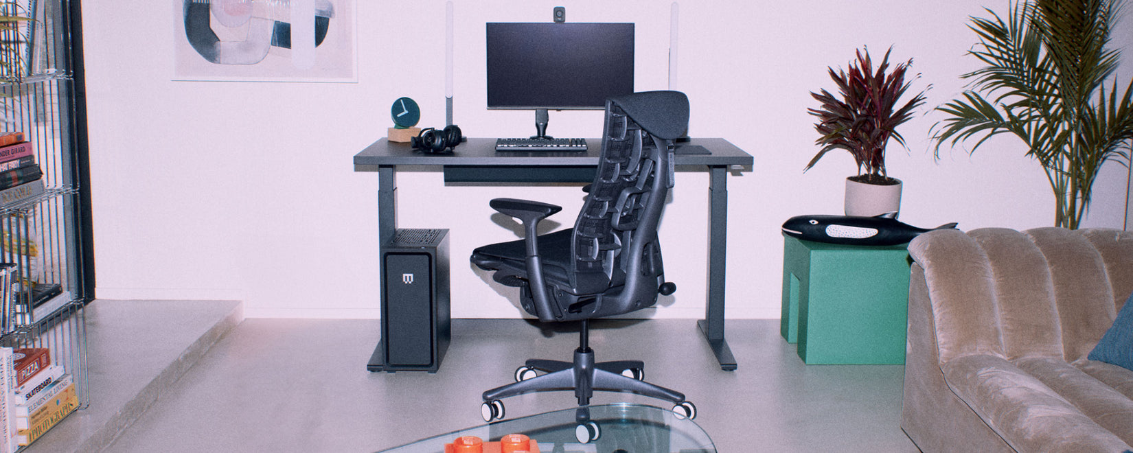Ein ergonomisches PC-Gaming-Setup mit einem schwarzem Embody Gaming Stuhl von Herman Miller und dem Sitz-Steh-Gaming-Schreibtisch Nevi in einem weißen, modernen Wohnzimmer.