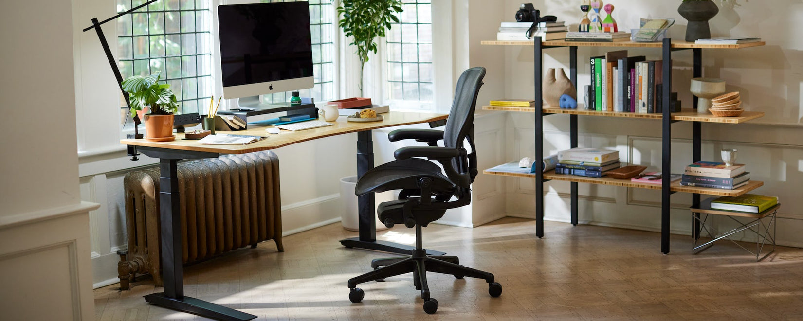 Home Office mit dem ikonischen Herman Miller Aeron Stuhl in Onyxschwarz und dem Sitz-Steh-Schreibtisch Jarvis mit Beinen und konturierter Bambusplatte.