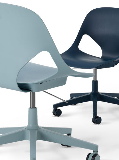 Zwei Herman Miller Zeph-Bürostühle, einer in Hellblau und einer in Dunkelblau.