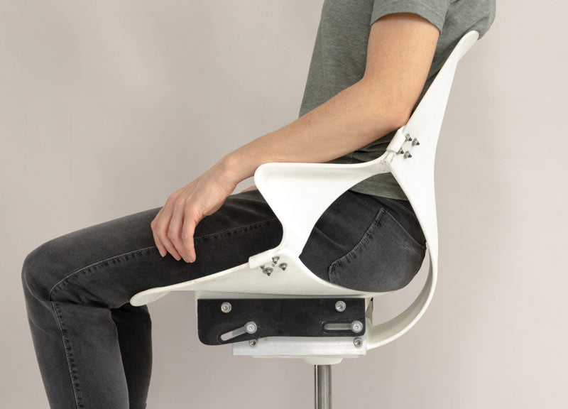 Seitenansicht einer Person, die auf einem noch unfertigen Zeph-Bürostuhl sitzt, die Flexibilität der Rückenlehne des Stuhls zeigt