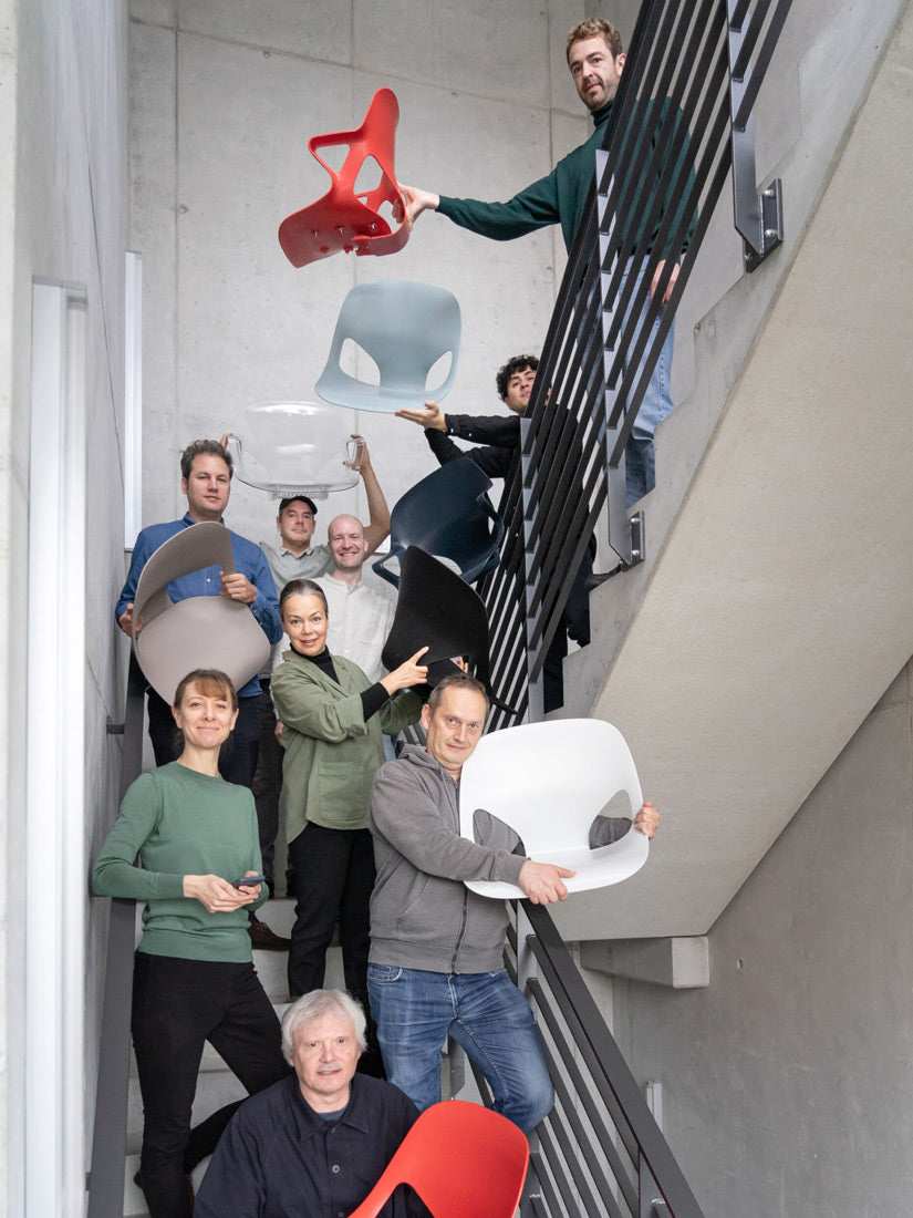 Foto von Mitgliedern des Designteams von Studio 7.5 in einem Treppenhaus, einige von ihnen halten verschiedene Teile des von ihnen entworfenen Herman Zeph-Stuhls in den Händen