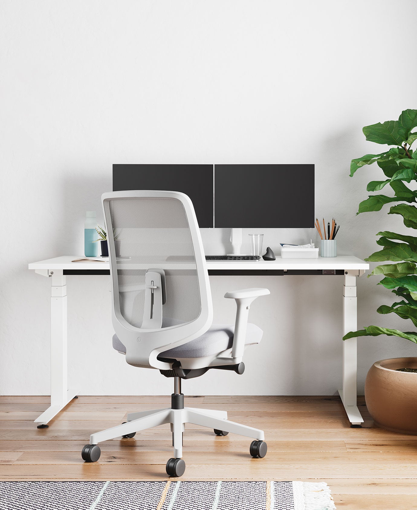 Home-Office mit Bürostuhl Verus in Mineralweiß mit hellgrauer Sitzauflage, vor Nevi-Sitz-Steh-Schreibtisch in Weiß mit zwei Bildschirmen auf Monitorarmen