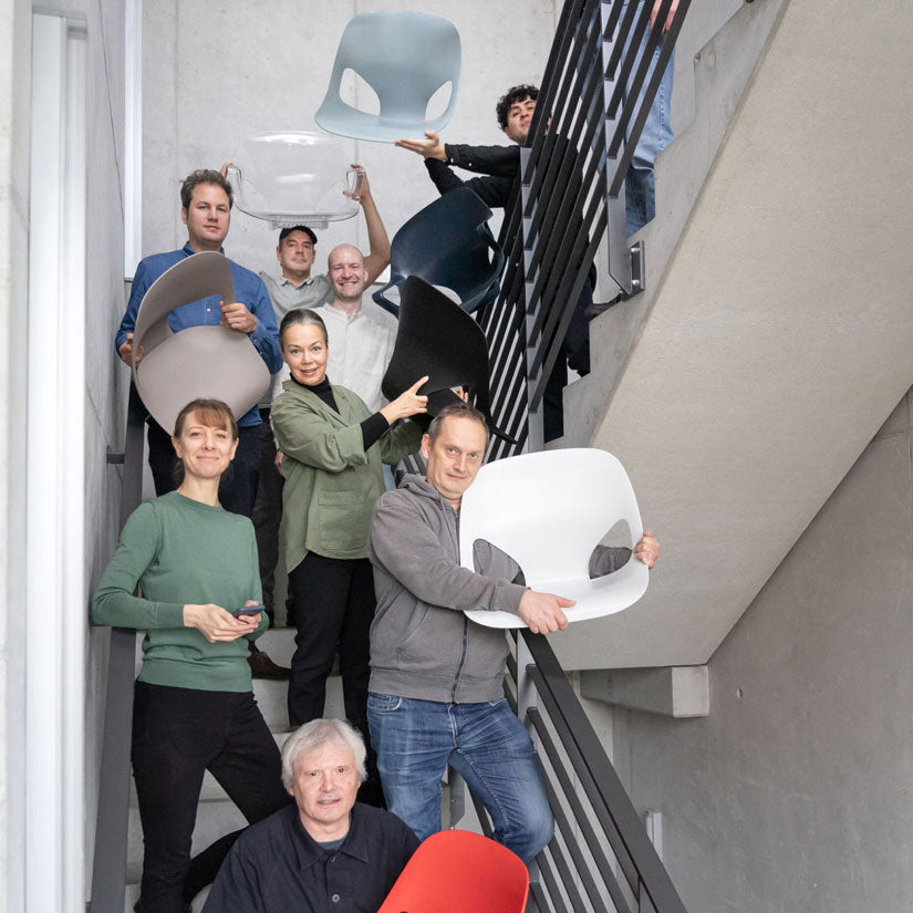 Foto von Mitgliedern des Studio 7.5-Designteams in einem Treppenhaus, die verschiedene Teile des von ihnen entworfenen Herman Zeph-Stuhls in der Hand halten