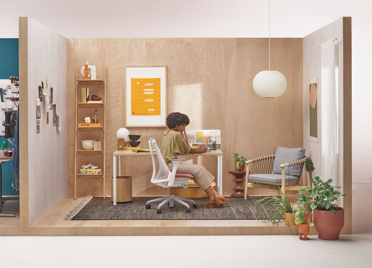 Frau sitzt an einem Schreibtisch in einem neutralen Homeoffice in einem weißen Sayl-Bürostuhl vor einem OE1-Schreibtisch mit weißen Beinen und heller Holzplatte