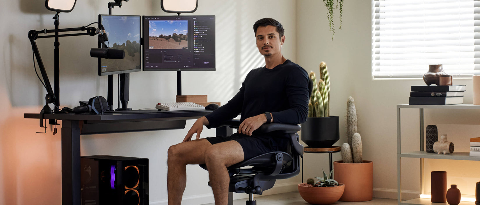 Bild des Gamers Xaryu, der in einem grauen Gaming-Stuhl Aeron mit einem Gaming-Setup aus einem Gaming-Tisch Nevi und zwei Monitorarmen Ollin vor der Kamera sitzt.