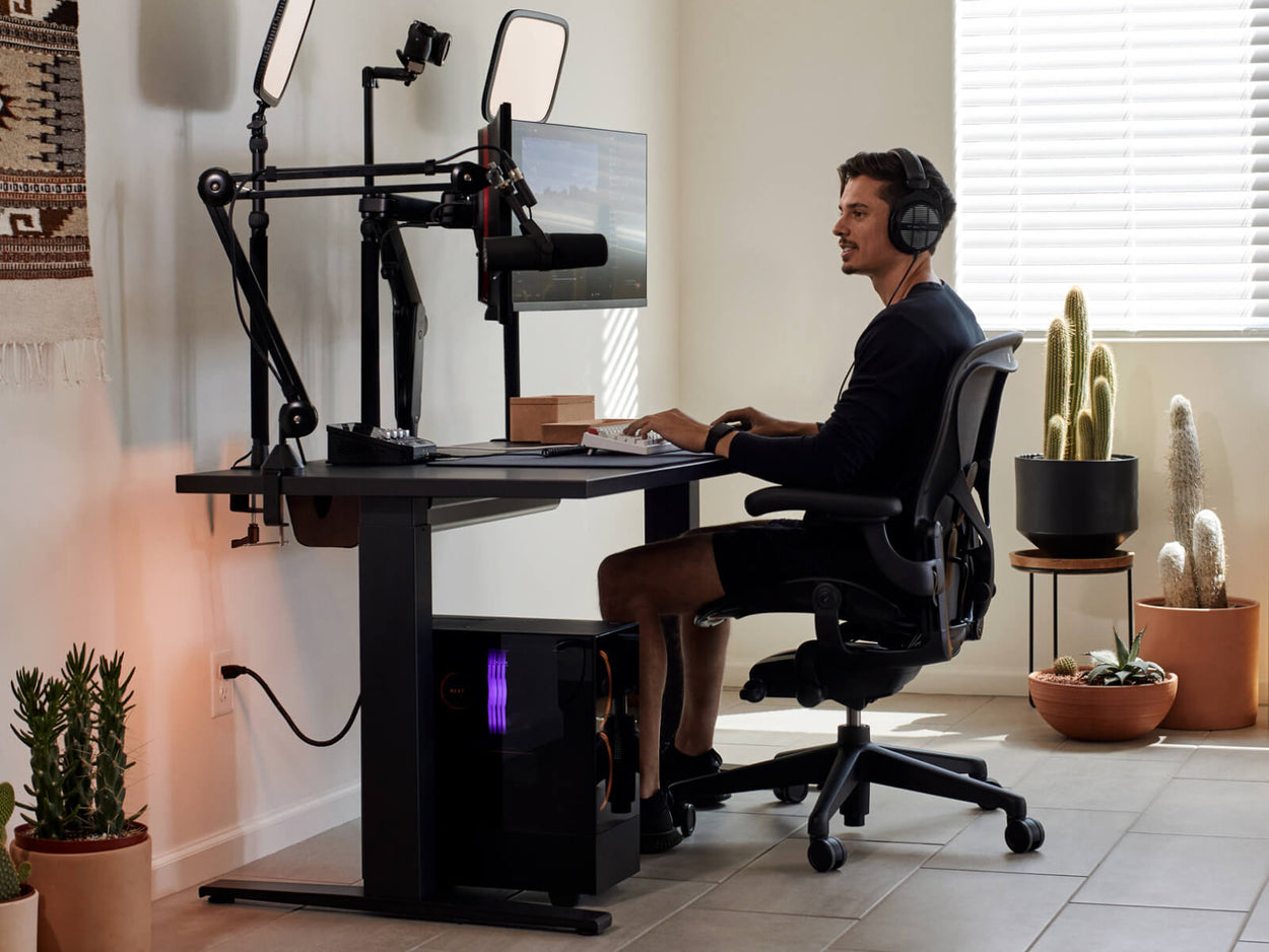Gamer Xaryu spielt an seinem Herman-Miller-Setup in einem Gaming-Stuhl Aeron mit einem Gaming-Tisch Nevi und zwei Monitorarmen Ollin.