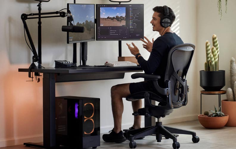 Gamer und Streamer Xaryu in einem Gaming-Setup auf einem Herman Miller Aeron-Gaming-Stuhl mit schwarzem Nevi-Sitz-Steh-Gaming-Tisch und zwei Monitoren an Ollin-Monitorarmen