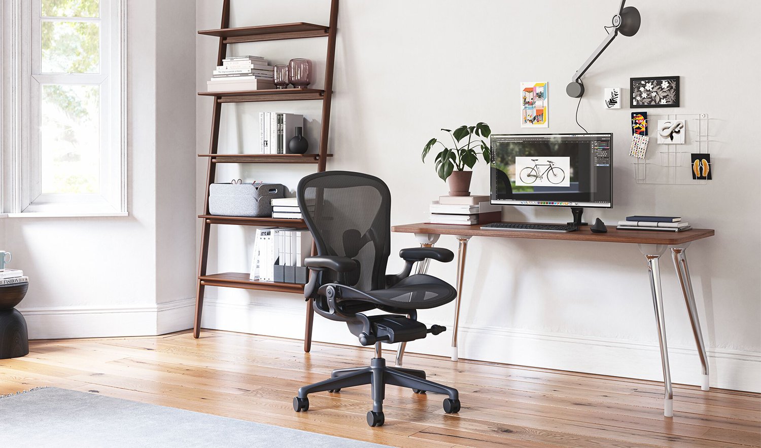 An AbakEnvironments Desk with a walnut top and polished legs, with a graphite Aeron Chair in a light home office setting and Folk Ladder Shelving.