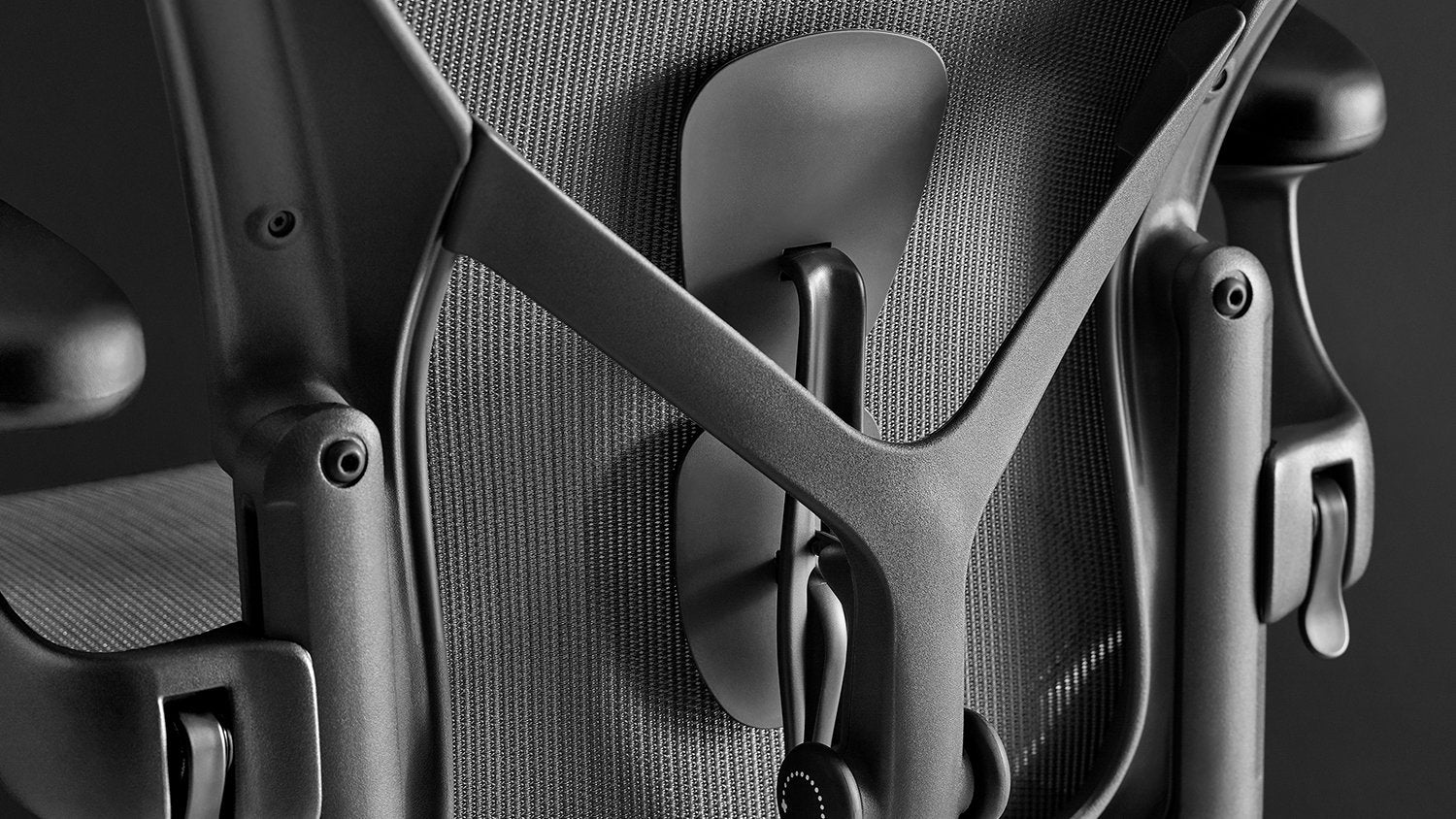 Rear view of a graphite Aeron office chair, showing back support and adjustable arms.