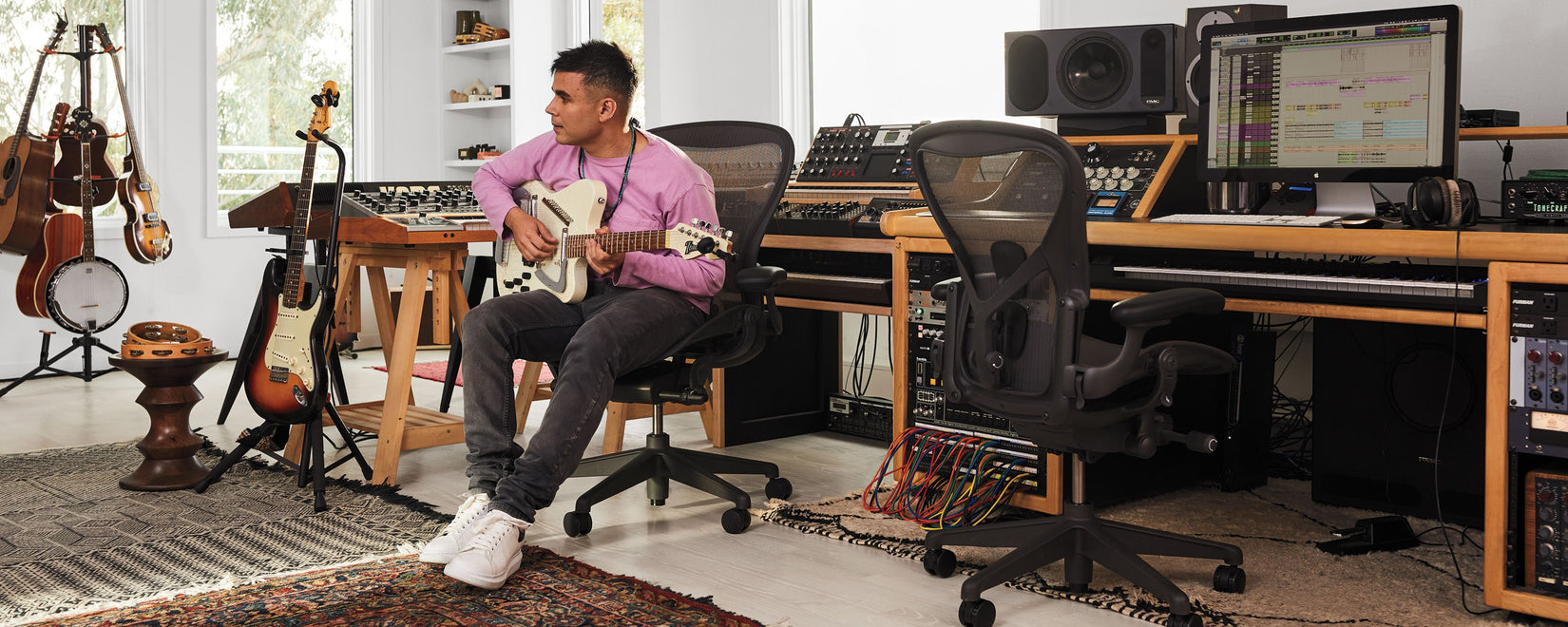 Rostam Batmanglij, Musiker, Produzent und Komponist, spielt in seinem Musikstudio eine Italia Modena Electric Sitar-Gitarre und sitzt dabei auf einem Aeron-Bürostuhl in Graphit.
